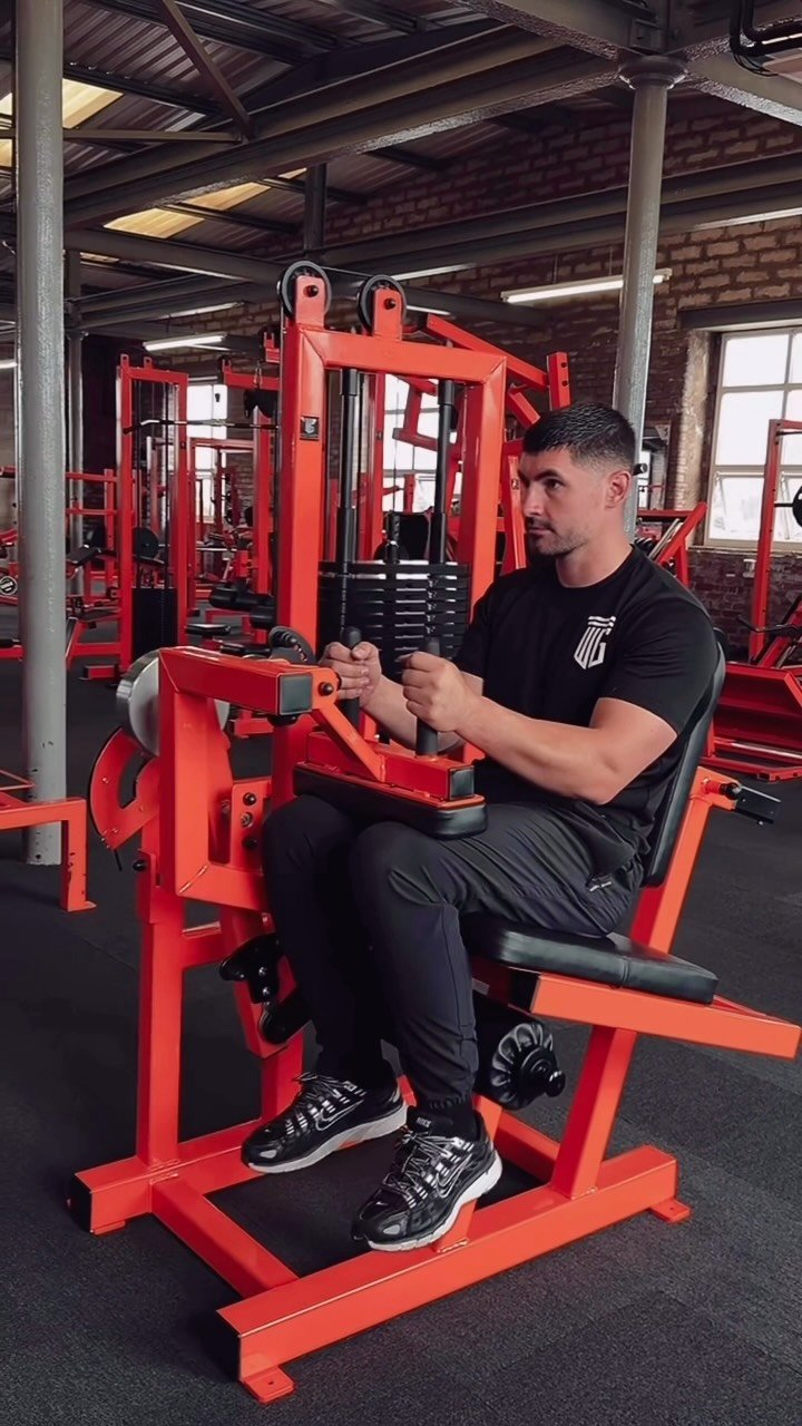 Cable-and-lever machine in orange WG frame with weight stack, mill windows behind